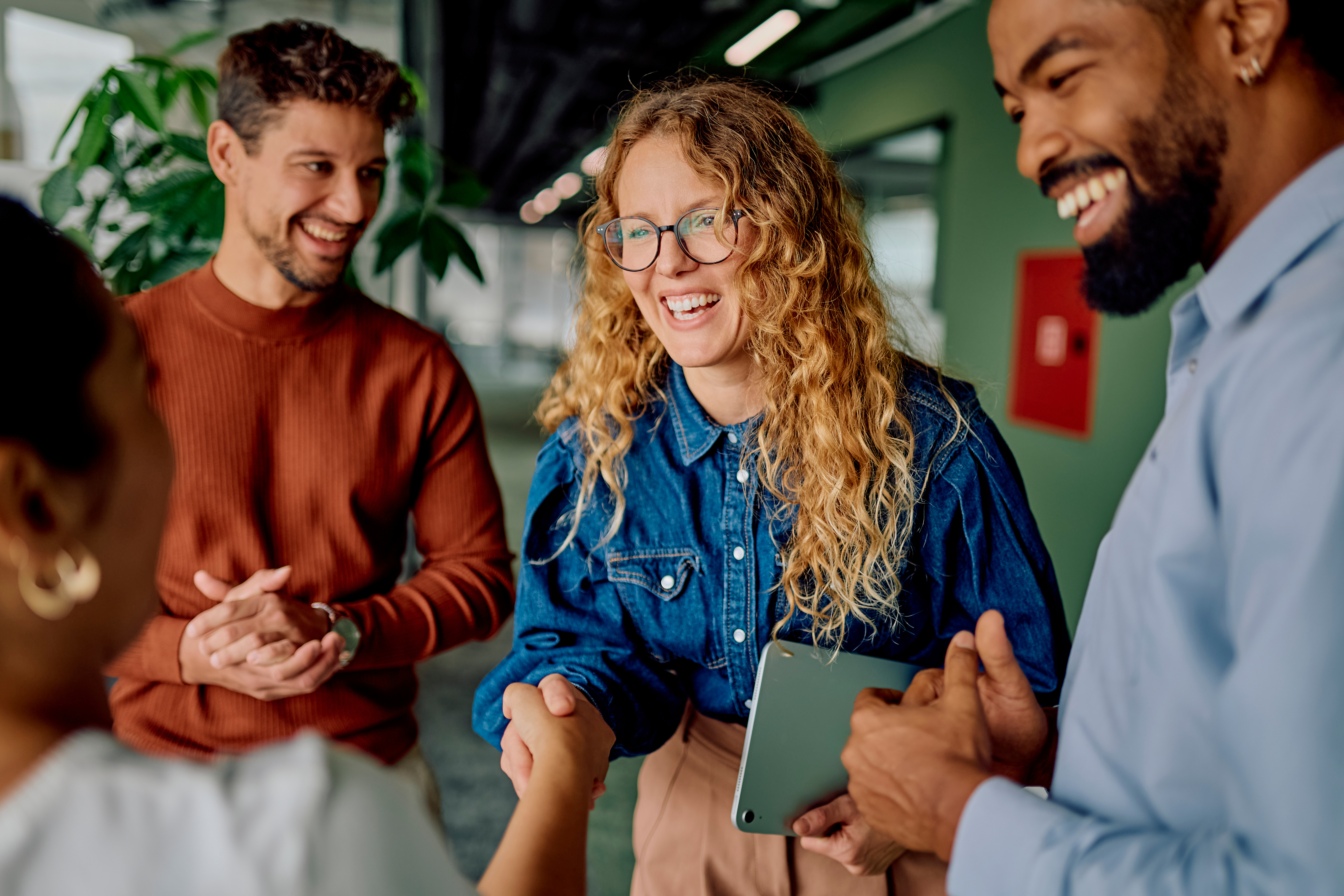 diverse-team-laughing-and-shaking-hands-in-office.jpeg