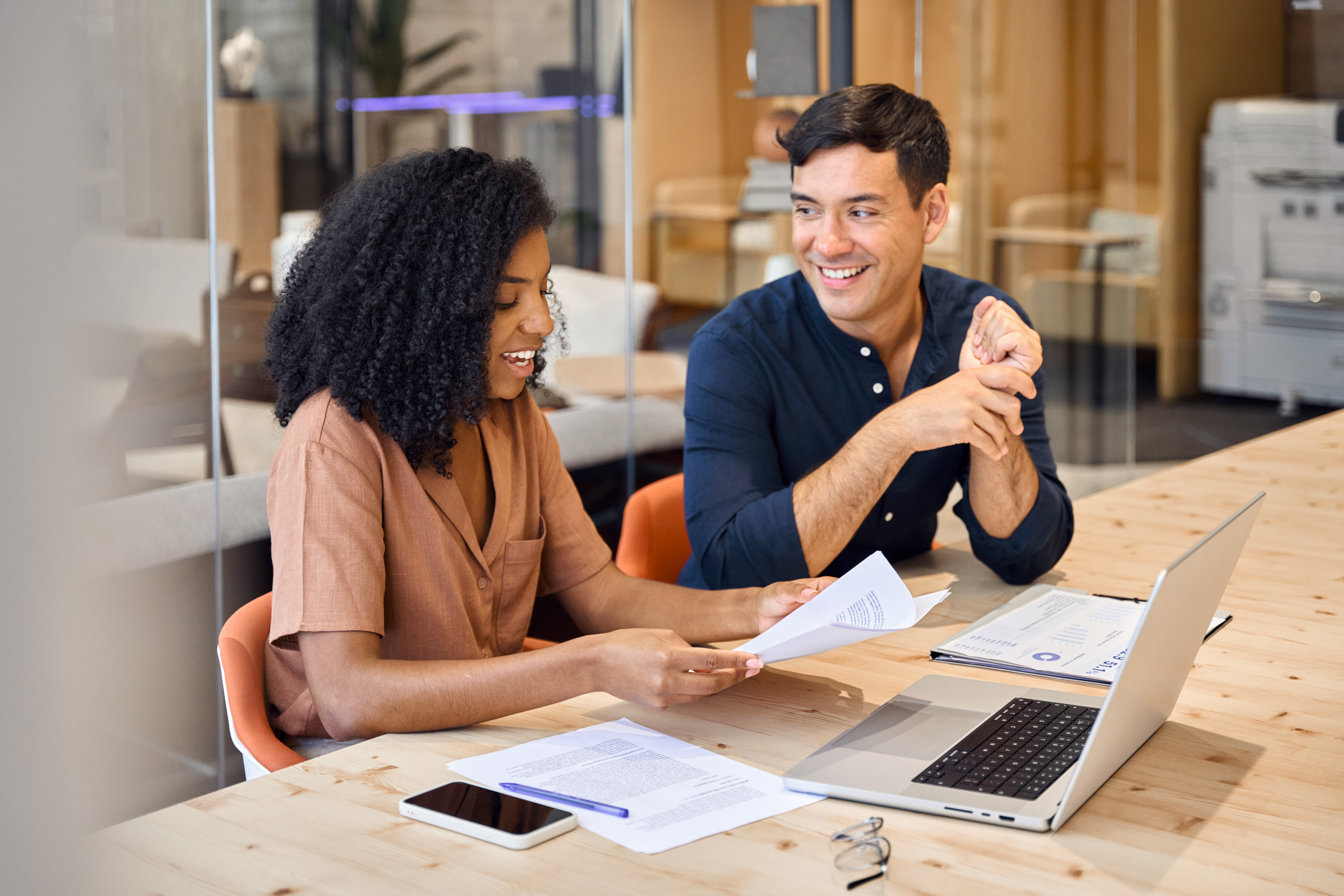 two-colleagues-smiling-and-reviewing-documents-with-laptop.jpeg
